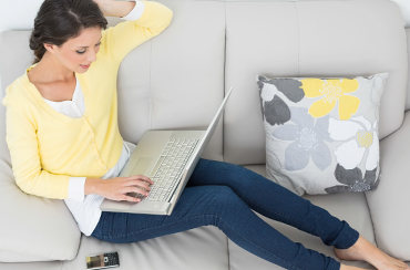 Woman laying on couch using laptop